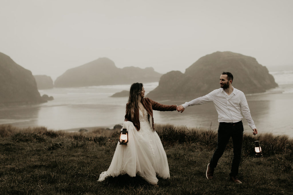 bride and groom walking with lanterns on Oregon coast