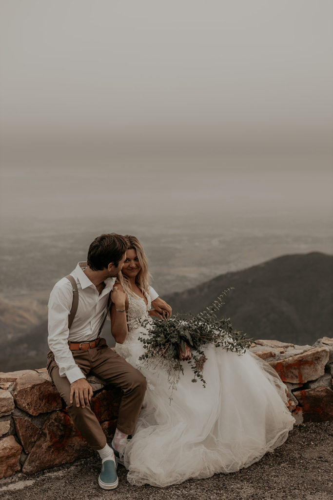 bride and groom sitting with mountain in the back