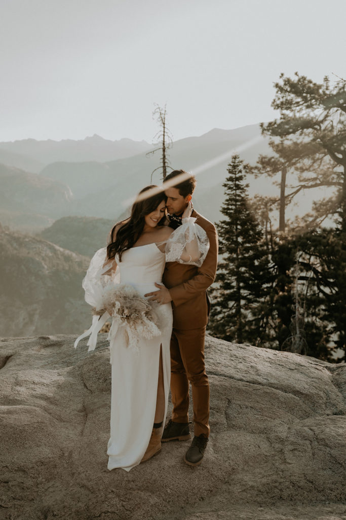 bride and groom on a rock at glacier point in Yosemite National Park