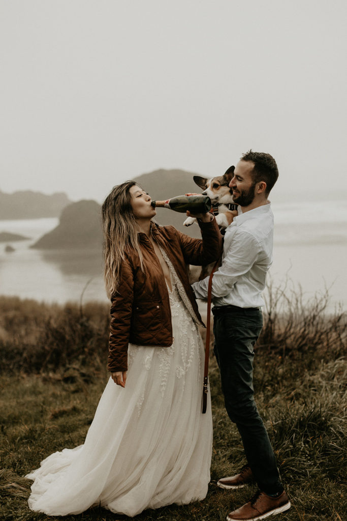bride drinking champagne and groom holding dog on Oregon coast