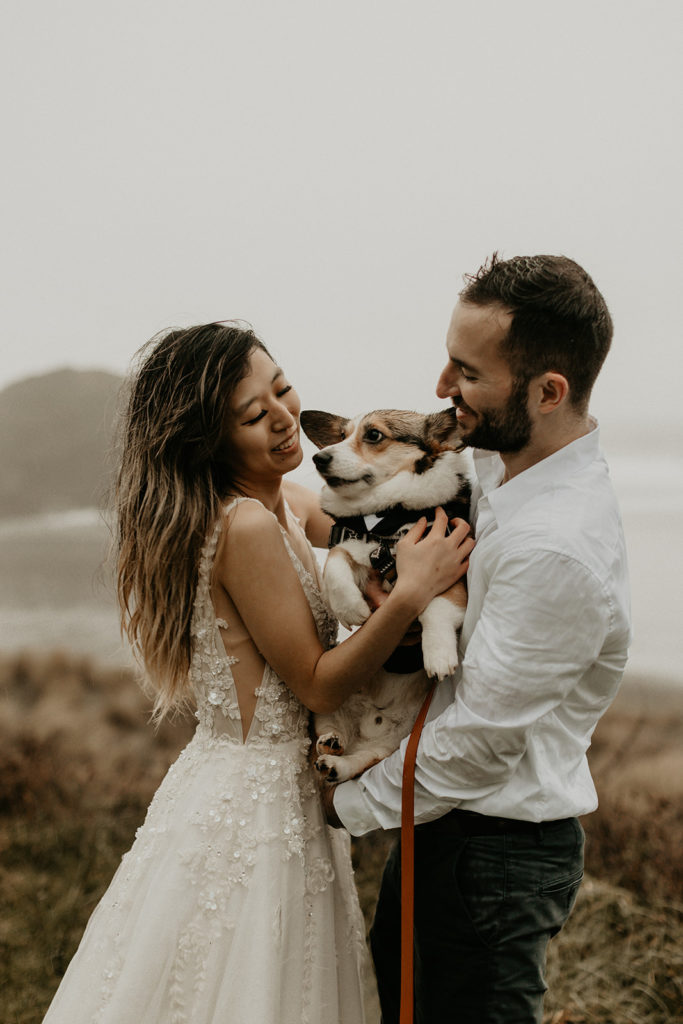 bride and groom holding dog on Oregon coast