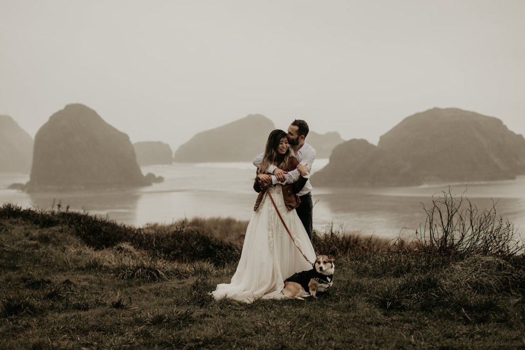 bride and groom cuddling with their dog on the Oregon coast