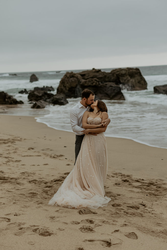 Groom standing behind Bride kissing at Big Sur