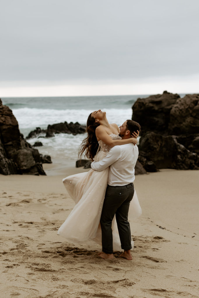 Groom spinning the Bride around on the sand of Big Sur